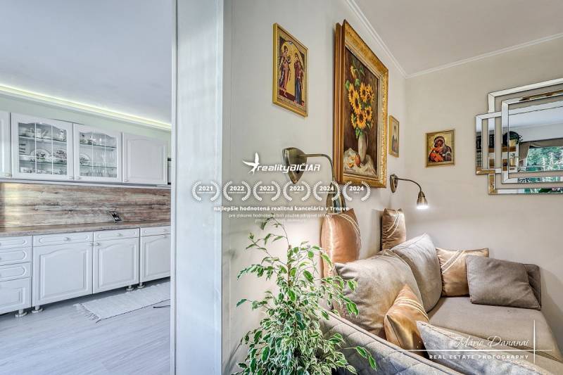 Interior of a family house with a white kitchen unit and a cozy corner with a sofa and decorations.