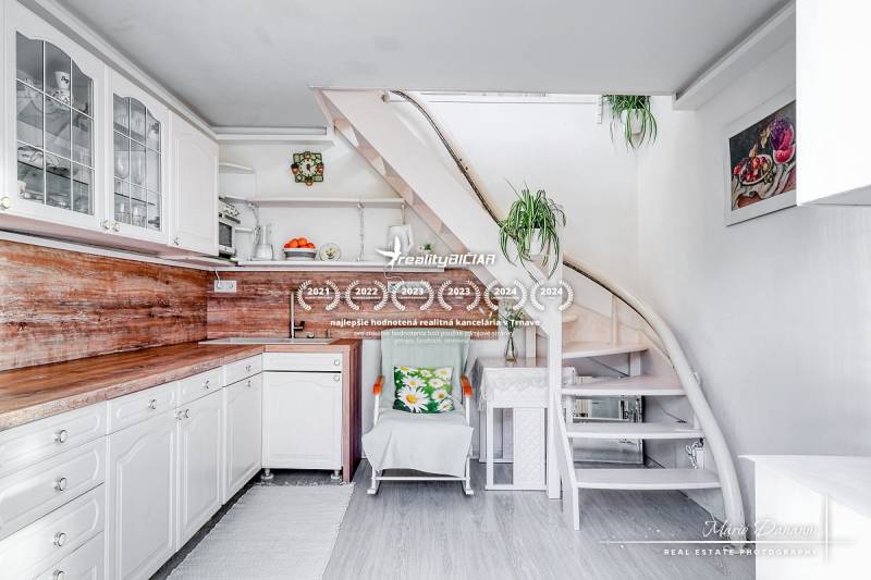 A kitchen in a family house with white furniture and a staircase, equipped with wooden decor.