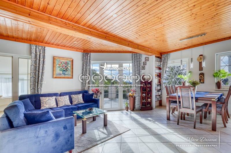 Living room in a cottage with a wooden ceiling, blue sofa, and dining table.