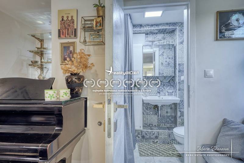 Interior of a cottage with a piano, decorations, and a bathroom with mosaic tiles.