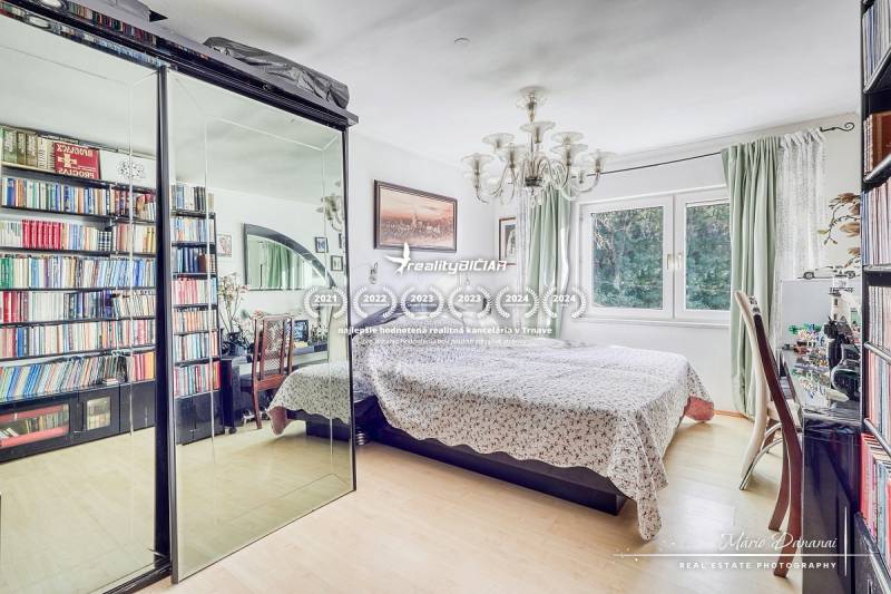 Bedroom with a bed, large mirrored wardrobe, and bookshelf, floor with wood decor.