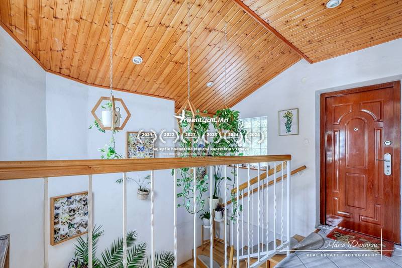 Lobby in a cabin with a wooden ceiling and abundant greenery, floor with wooden decor.