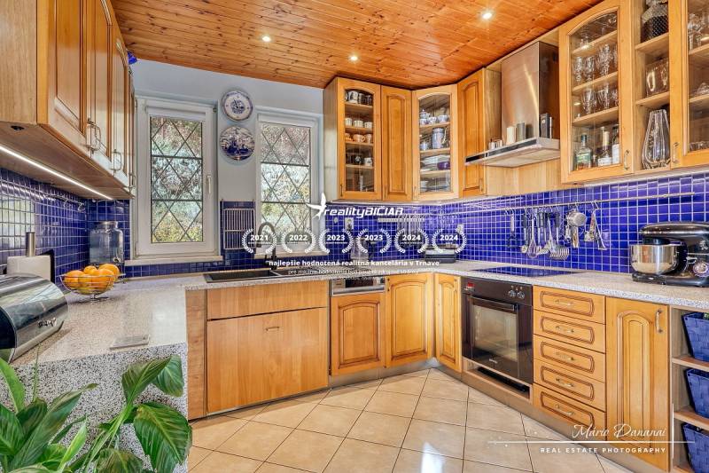 A kitchen in a family house with a wooden ceiling, blue tiles, and a wooden decor kitchen unit.