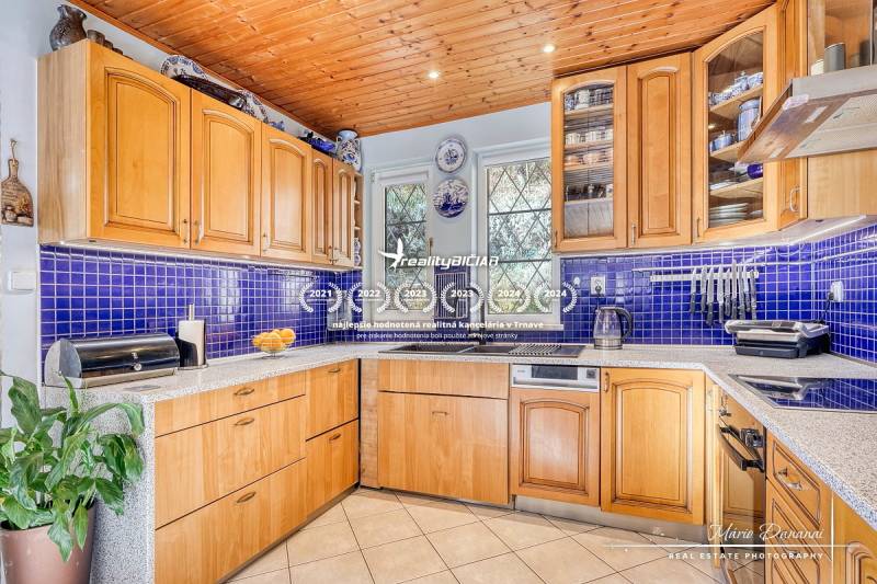 A kitchen in a cottage with wooden decor, blue tiles, and appliances.