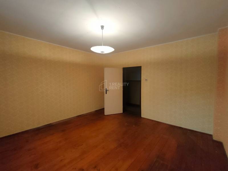 A room in a family house with a wooden decor floor and light-colored walls.