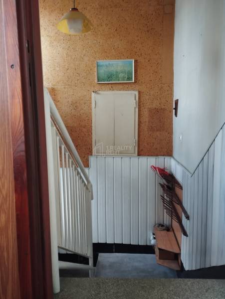 A staircase in a family house with cork walls and a shoe rack.