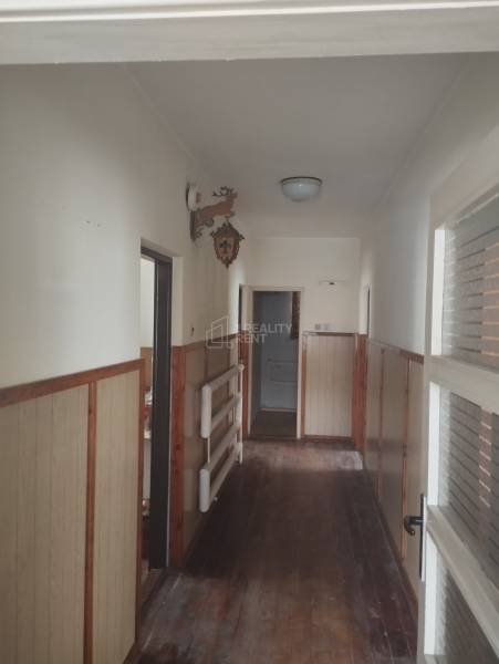 A hallway in a family house with a wooden decor floor and wooden wall paneling.