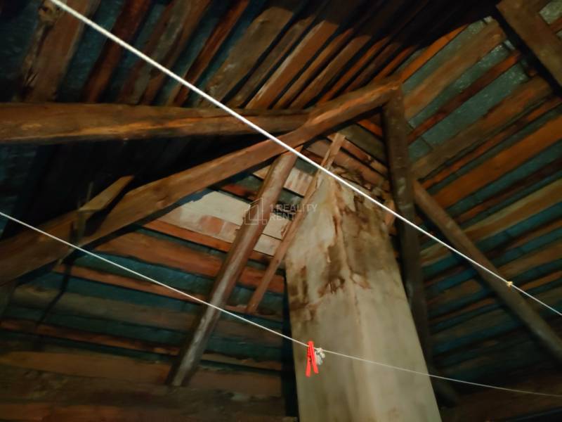 Rafters and walls in the attic of a family house, view of wooden beams and chimney.
