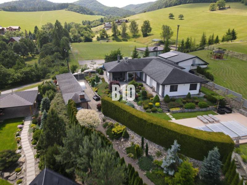 A villa in Súľov-Hradná surrounded by a beautiful garden and hilly landscape.