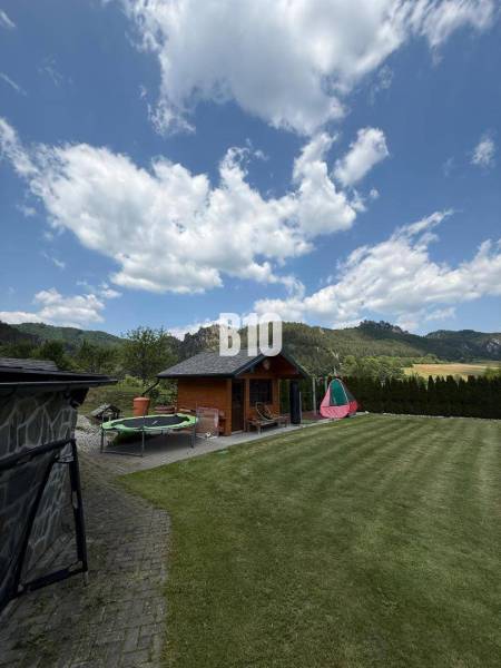 A garden with a cottage and a trampoline in a villa in Súľov-Hradná.