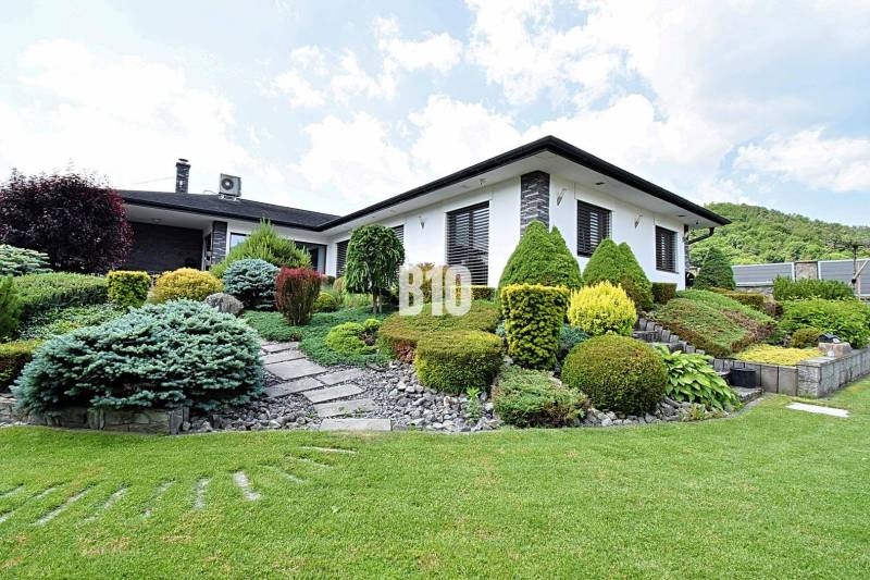 A villa in Súľov-Hradná with a beautiful garden and manicured shrubs.