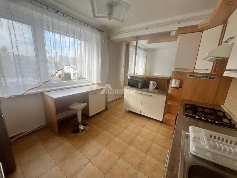 A kitchen in a 3-room apartment with a tiled floor and furniture with a wooden decor.