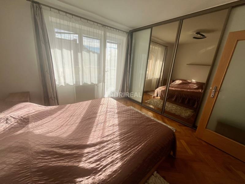 A bedroom in a 3-room apartment with a wooden decor floor and a mirrored wardrobe.