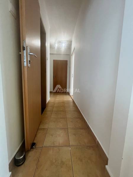 A hallway with tiles in a 3-room apartment, doors and white walls.