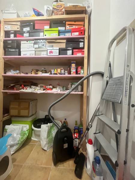A warehouse with shelves, boxes, a vacuum cleaner, and a ladder in a 3-room apartment.