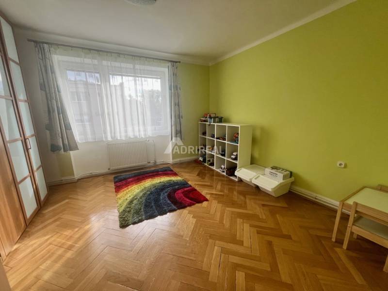 A room with a colorful carpet and a wooden decor floor in a 3-room apartment.