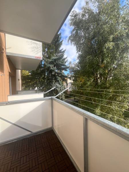 The balcony of a 3-room apartment on Majakovského Street in Lučenec with trees and a blue sky.