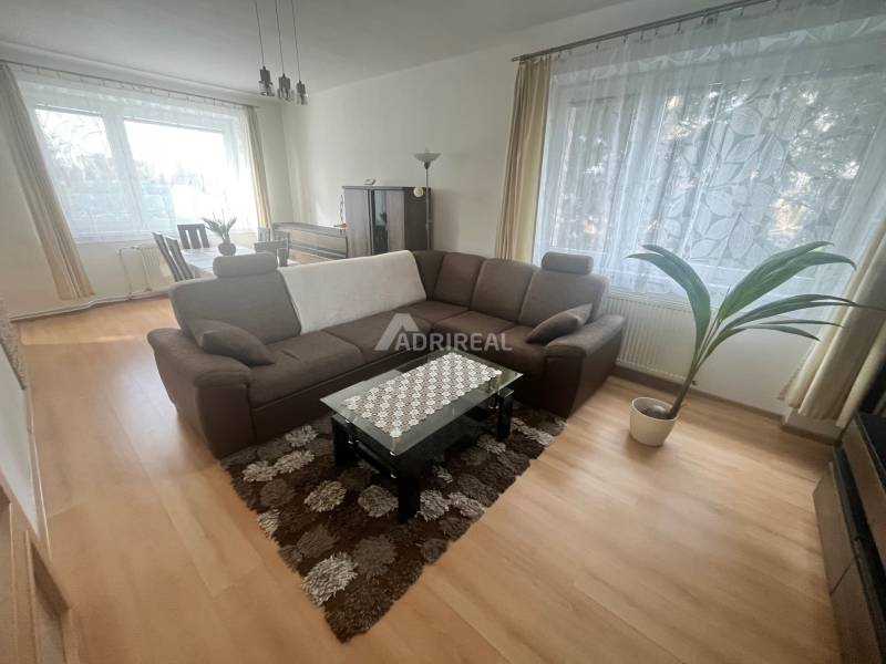 Living room with a sofa, table, and wood-patterned floor in a 3-room apartment.