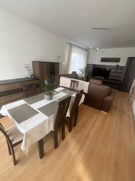 Dining room in a 3-room apartment with a sofa, wood-patterned flooring, and a television.