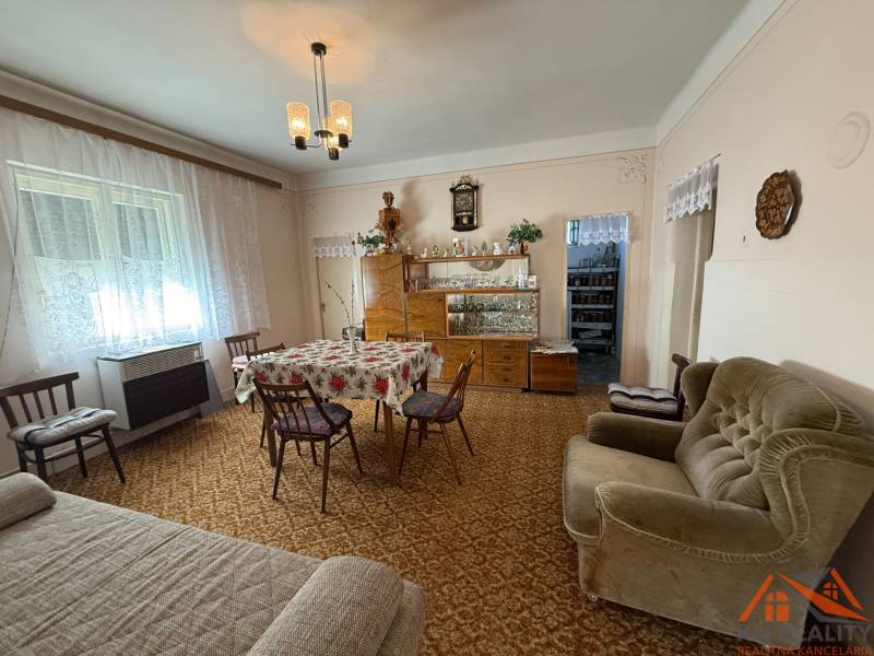 Living room in a family house with carpeted floor, floral tablecloth, and retro furniture.