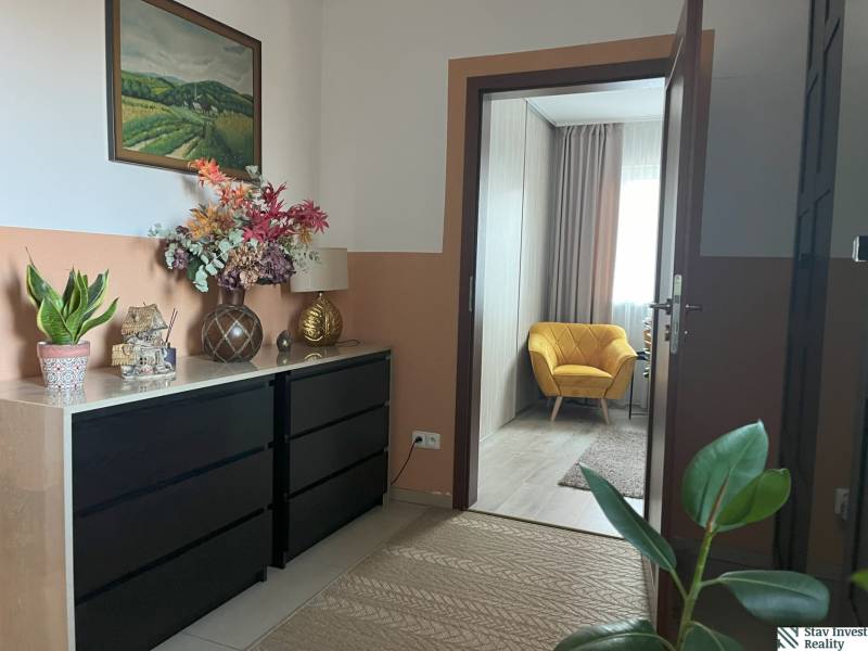 In the hallway of the 2-room apartment, there is a cabinet, decorations, and a yellow chair.