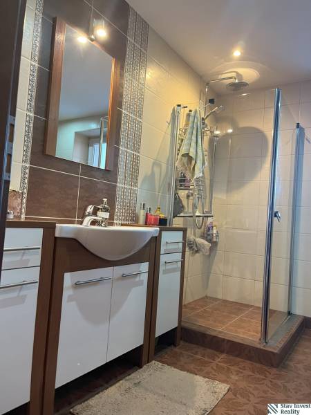 Bathroom of a 2-room apartment with a shower, sink, and cabinets.