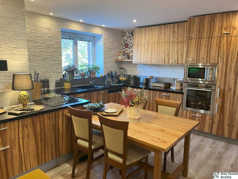 A kitchen in a 2-room apartment with built-in appliances and wooden furniture.