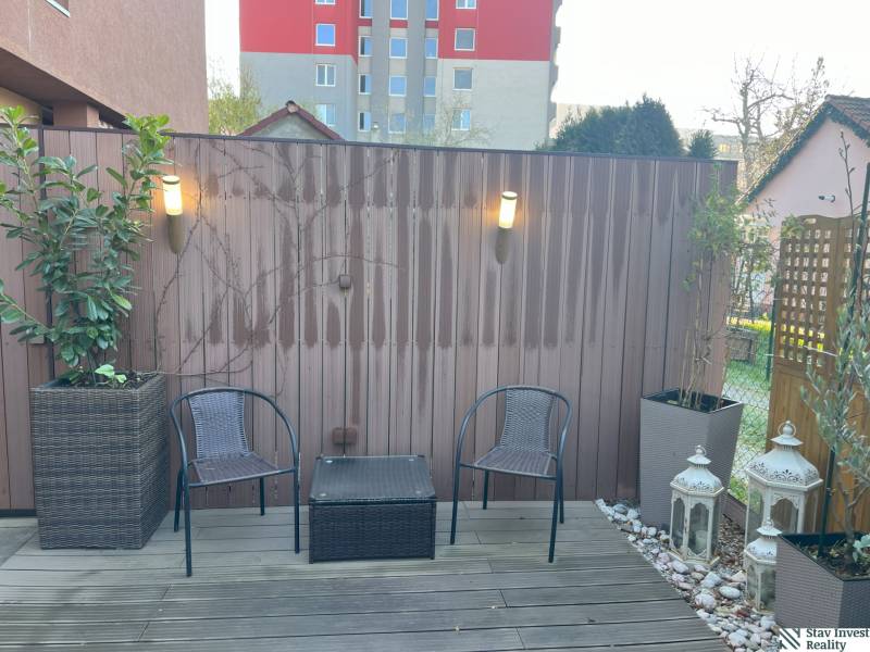 Terrace in Ružinov with wooden flooring, chairs, lights, and decorative lanterns.