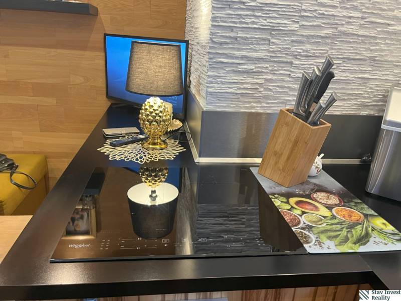 A kitchen in a 2-room apartment with a cooktop, knives, and a decorative lamp.