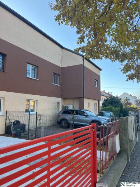 Two-story apartment building in Bratislava - Ružinov, with a parking lot and a red fence.