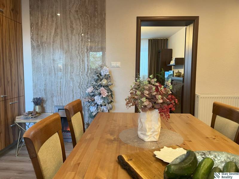 Dining table with flowers, decorated tree, and kitchen in a 2-room apartment.