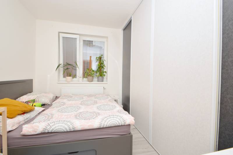 Bedroom with a bed, wardrobe, and plants in a 3-room apartment.