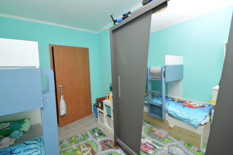 A children's room in a three-room apartment with a bunk bed and a colorful carpet on the floor.
