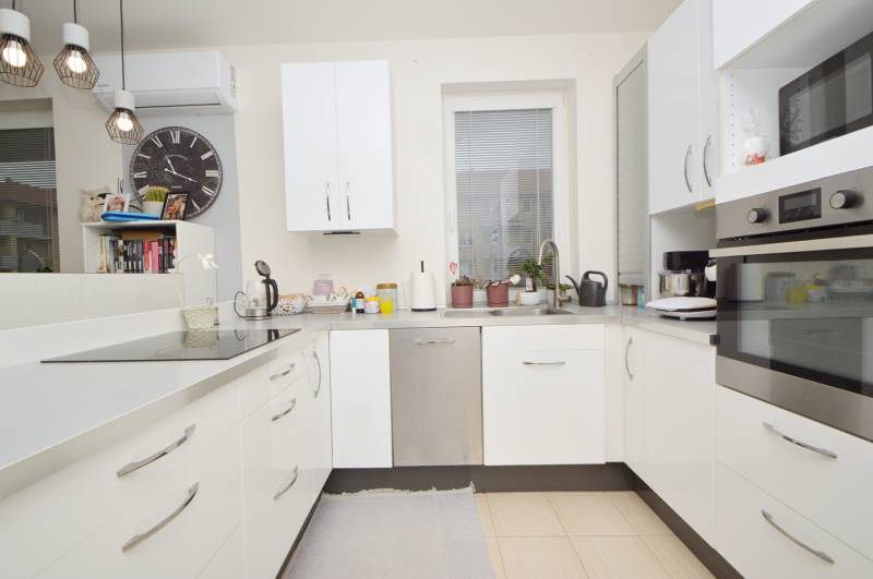 A kitchen in a 3-room apartment with white cabinets and built-in appliances.