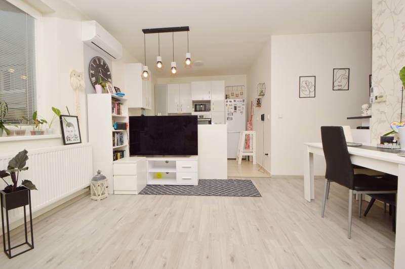 Living room of a 3-room apartment with a wood-decor floor, bright interior and furniture.