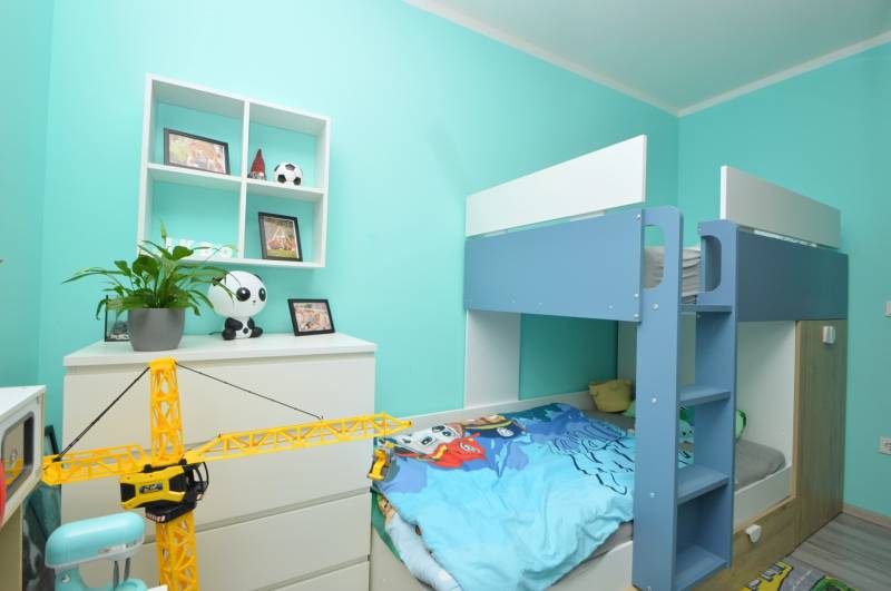 Children's room in a 3-room apartment with a bunk bed, toys, and turquoise walls.