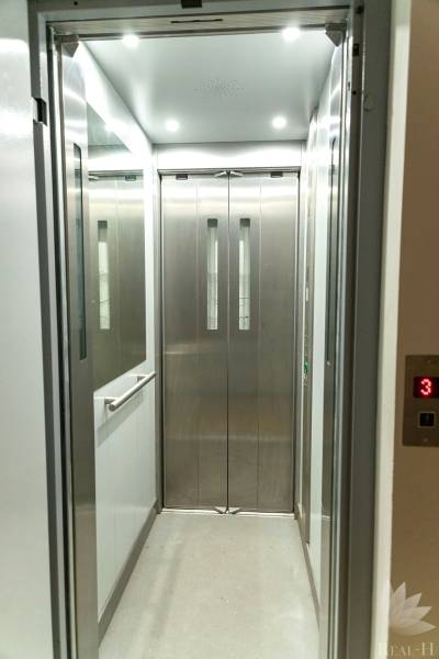 Elevator cabin with metal doors and energy-saving LED lights.