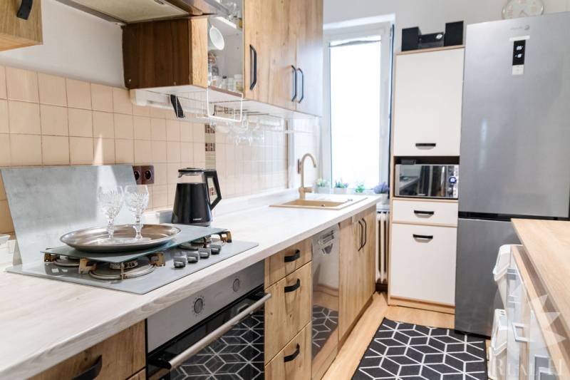 A kitchen in a 3-room apartment with a gas stove and white cabinets.