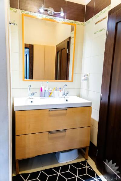 A bathroom with two sinks and a wooden cabinet in a three-room apartment.