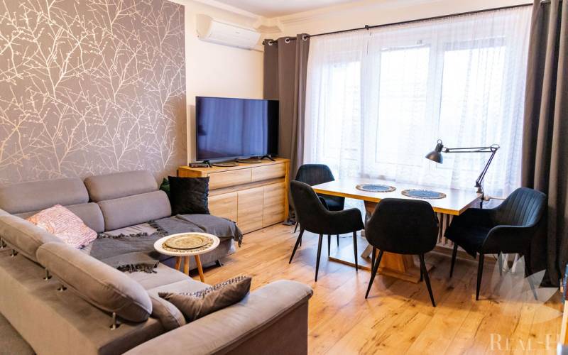 Living room in a 3-room apartment with a comfortable couch, wooden table, and floor with a wooden decor.