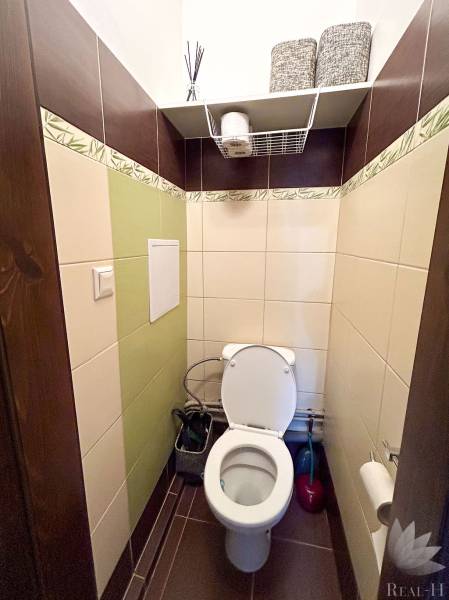 A toilet with tiles and storage space in a 3-room apartment.