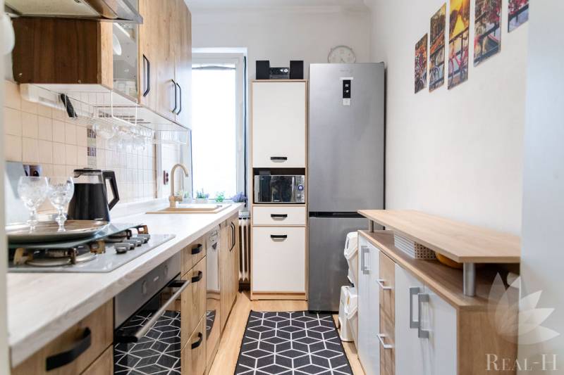 Kitchen in a 3-room apartment with appliances and flooring with a wood decor.