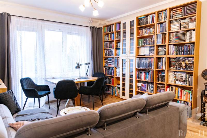 Living room in a 3-room apartment with a bookshelf and wooden decor flooring.