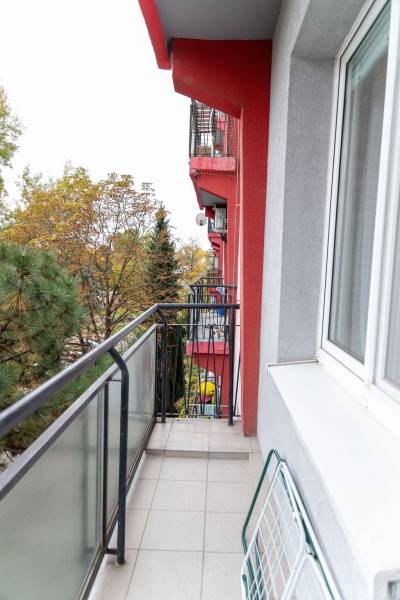 Balcony of a 3-room apartment with a view of greenery, red facade, window sill.