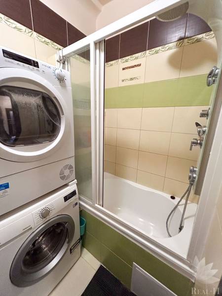 A bathroom in a 3-room apartment with a bathtub, washing machine, and dryer, tiles in earthy colors.