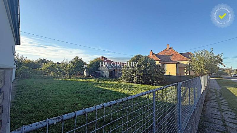 A plot for living in Kameničná with flat terrain and a house in the background.