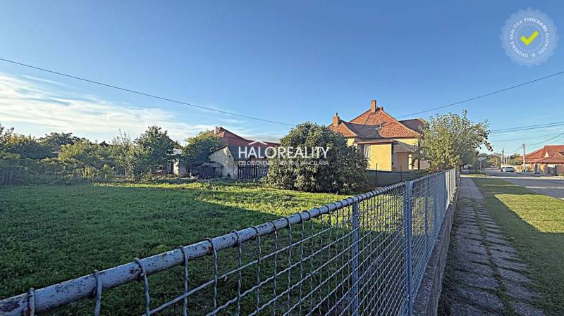 A residential plot in Kameničná with fencing, a house, and a garden by the road.