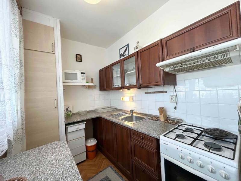 A kitchen in a 2-room apartment with a kitchen unit, a range hood, and a gas stove.