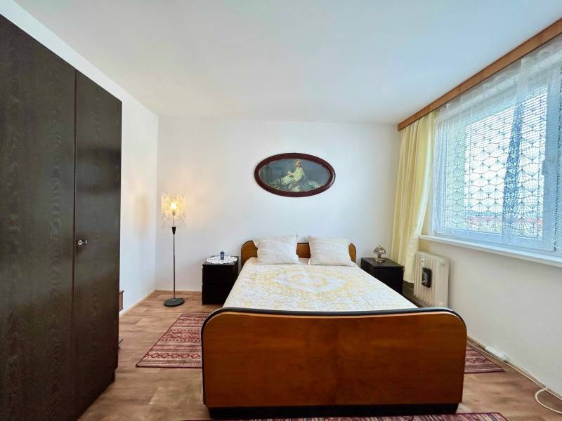 Bedroom in a 2-room apartment, wooden wardrobe, bed, lamps, and decorative curtains.