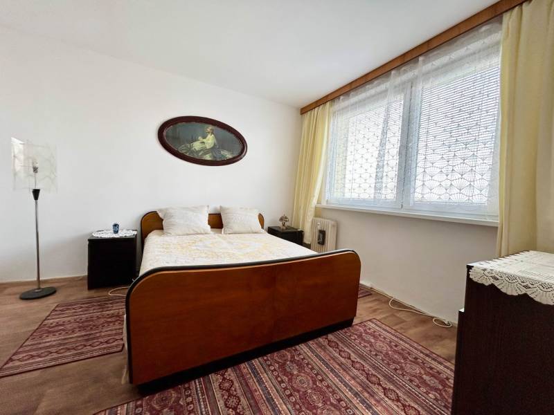 Bedroom in a 2-room apartment with a bed, name on the wall, large window, and carpets.